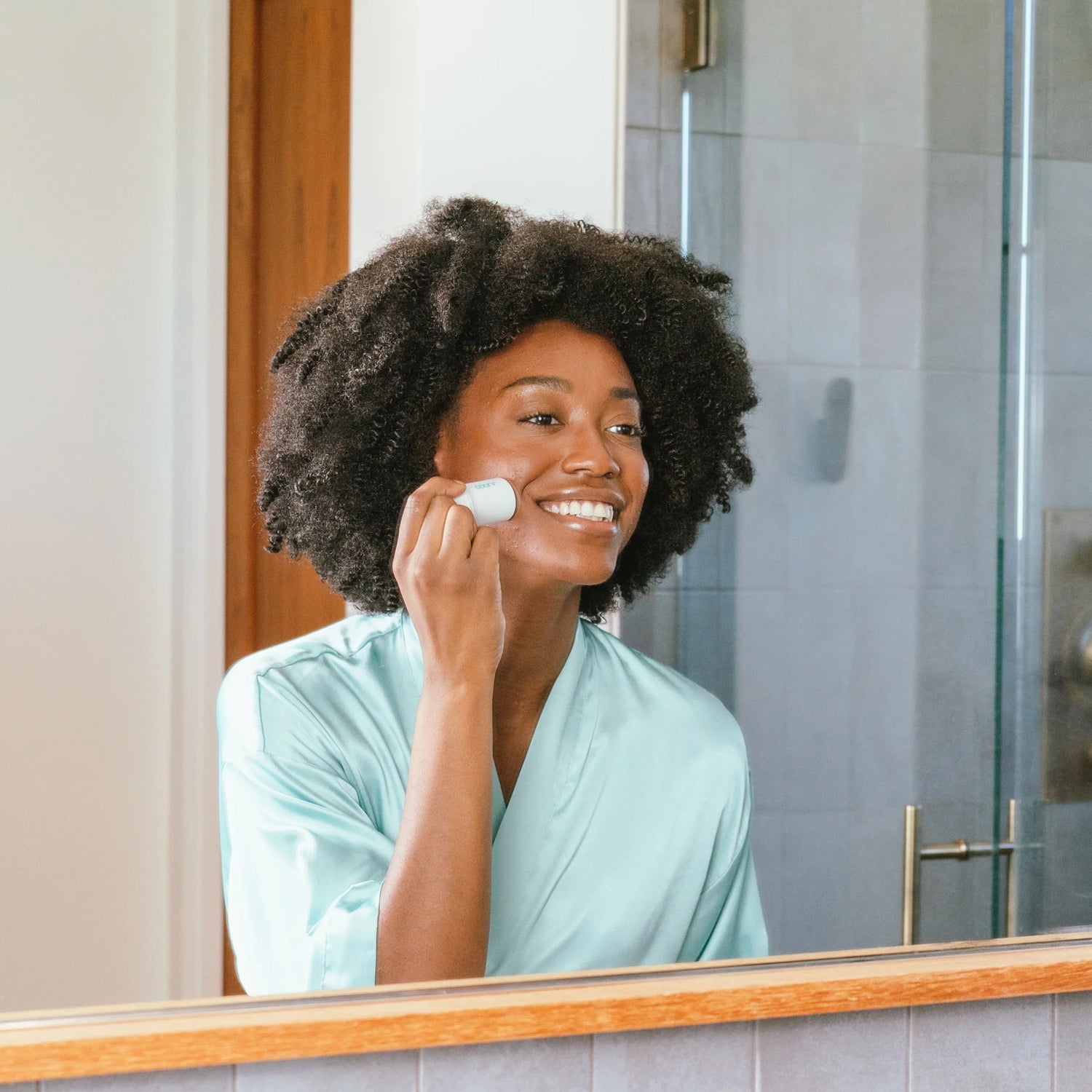 Woman applying Refreshing Water Hydration Stick organic face sunscreen in front of mirror