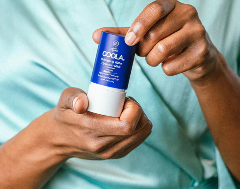 Person holding Coola Refreshing Water Hydration Stick with SPF 50, organic face sunscreen stick for weightless hydration and sun protection.
