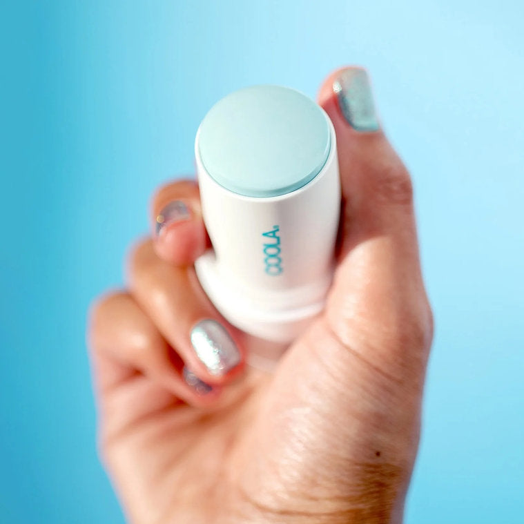 Refreshing Water Hydration Stick Organic Face Sunscreen SPF 50 held in hand against blue background.