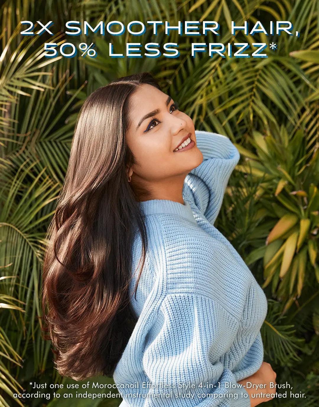 Woman with smooth, frizz-free hair using a 4-In-1 Blow-Dryer Brush, in lush garden setting showing hair care results.