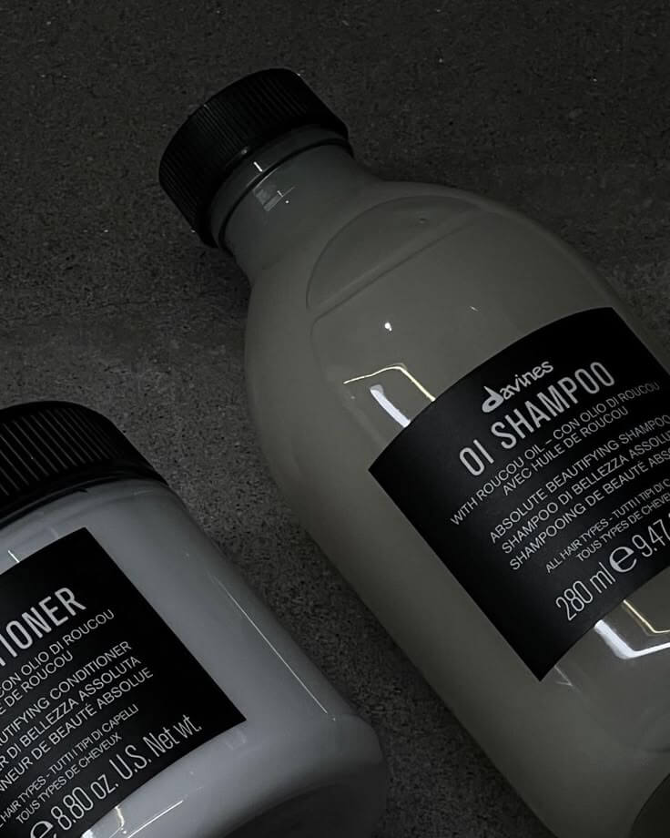 Davines OI Shampoo and Conditioner bottles on a dark surface, emphasizing beauty care products.