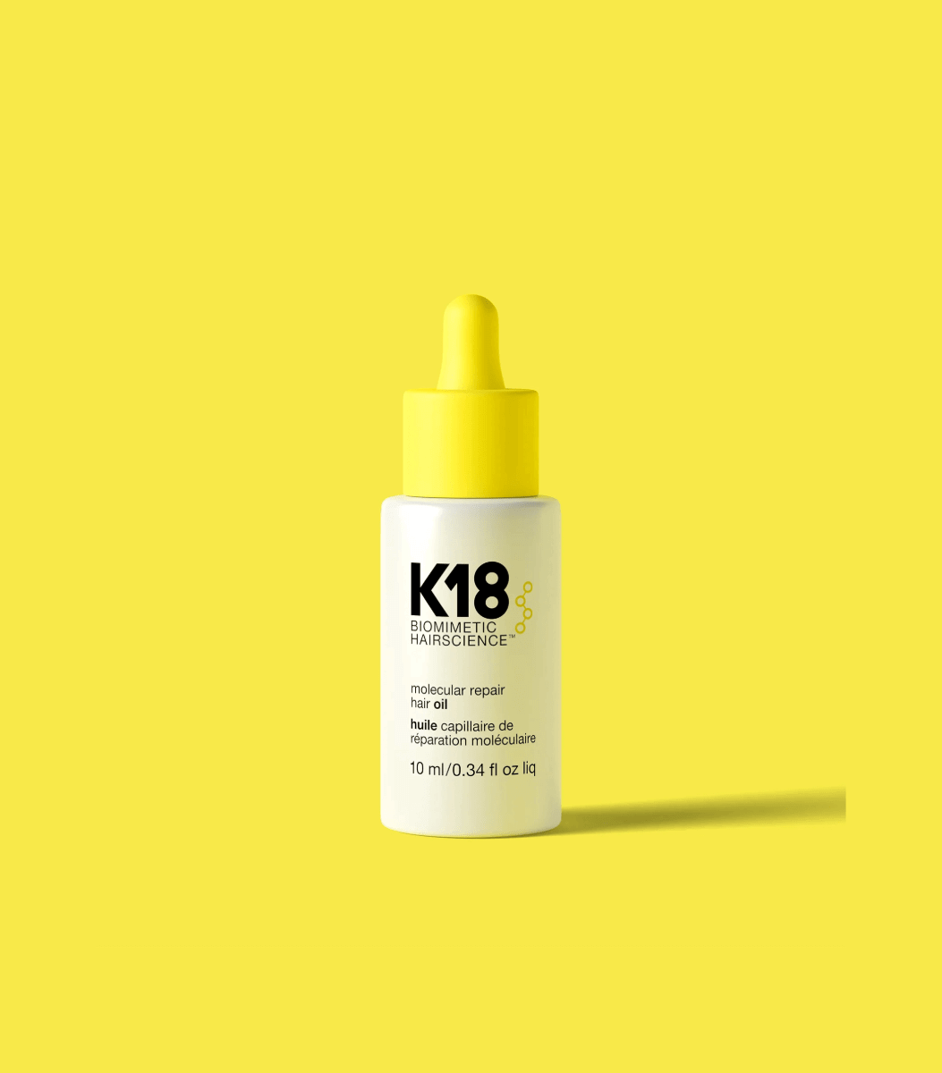 Molecular Repair Hair Oil bottle against yellow background, designed for damage repair, frizz control, and shine enhancement.