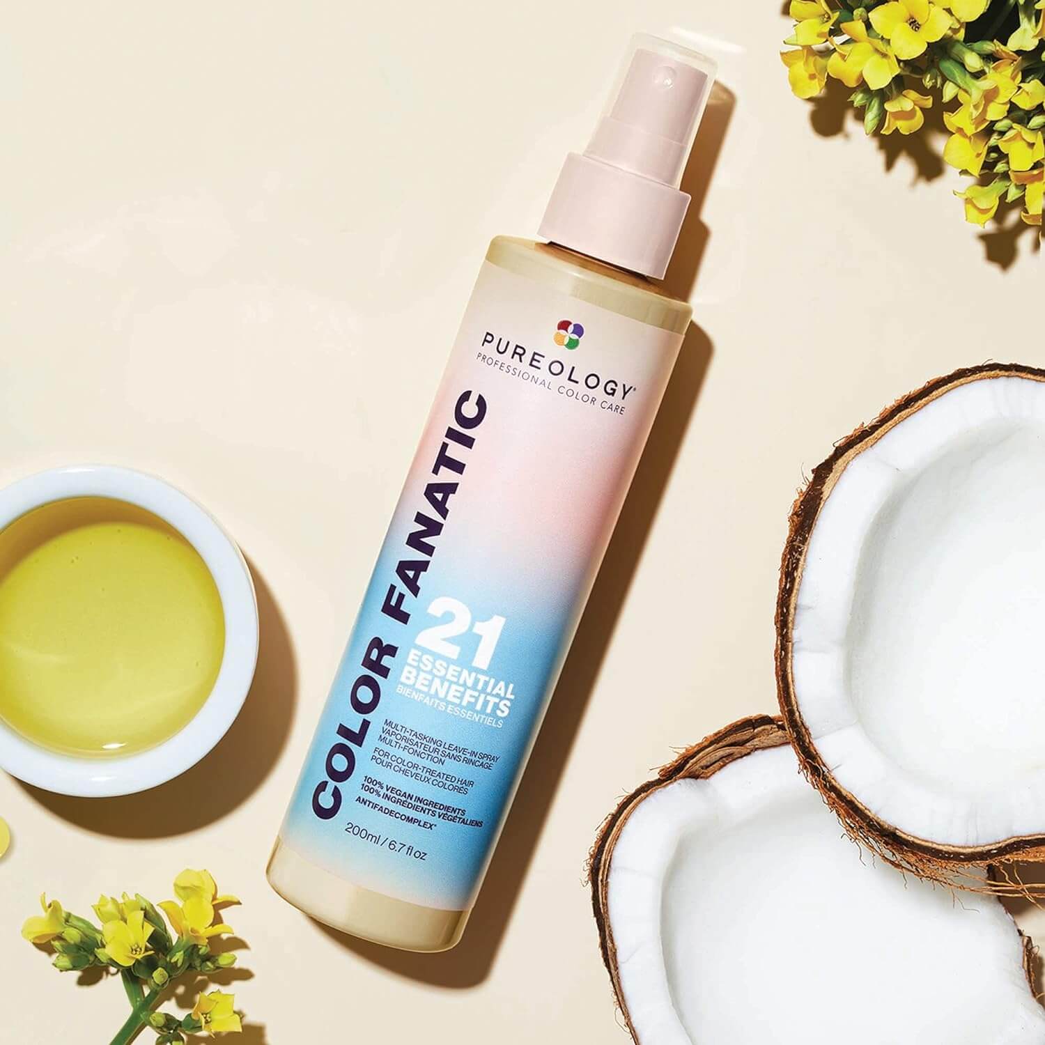 Pureology Colour Fanatic spray alongside coconuts and greenery, showcasing its 21 benefits for colour-treated hair.