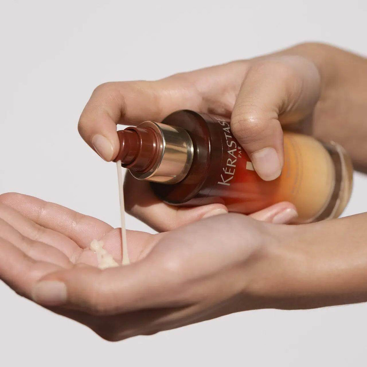 Person applying Kérastase 8H Magic Night Serum for dry hair nourishment.