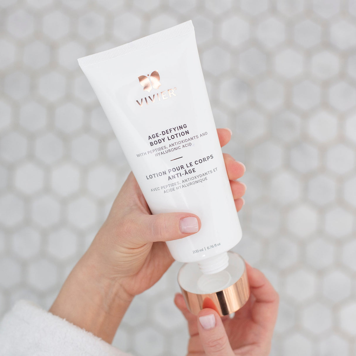 Vivier Age-Defying Body Lotion held in hands, firms and hydrates skin, enriched with peptides and antioxidants for silky smooth finish.
