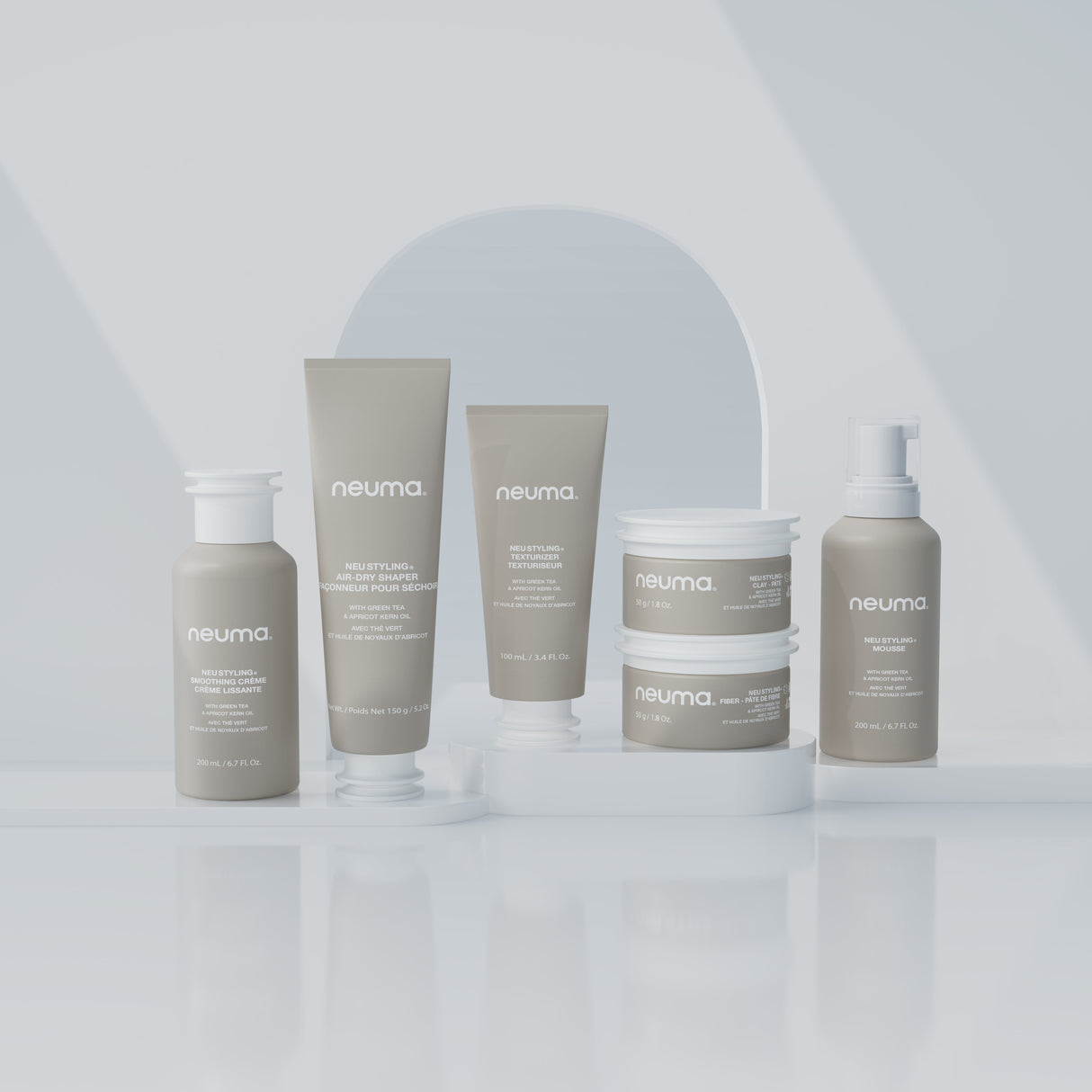 Collection of Neuma hair care products displayed on a reflective surface with minimalist background.