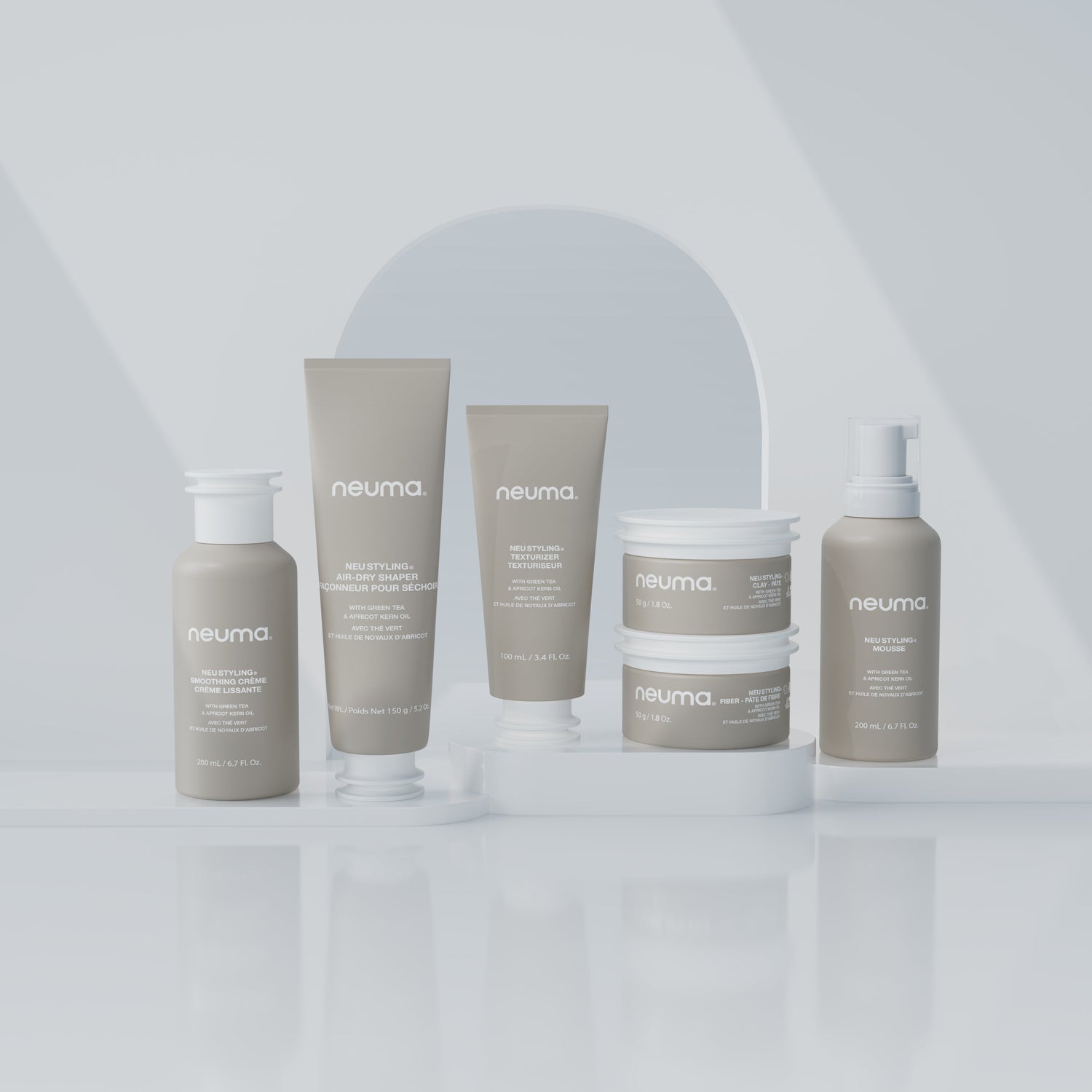 Collection of Neuma hair care products displayed on a reflective surface with minimalist background.