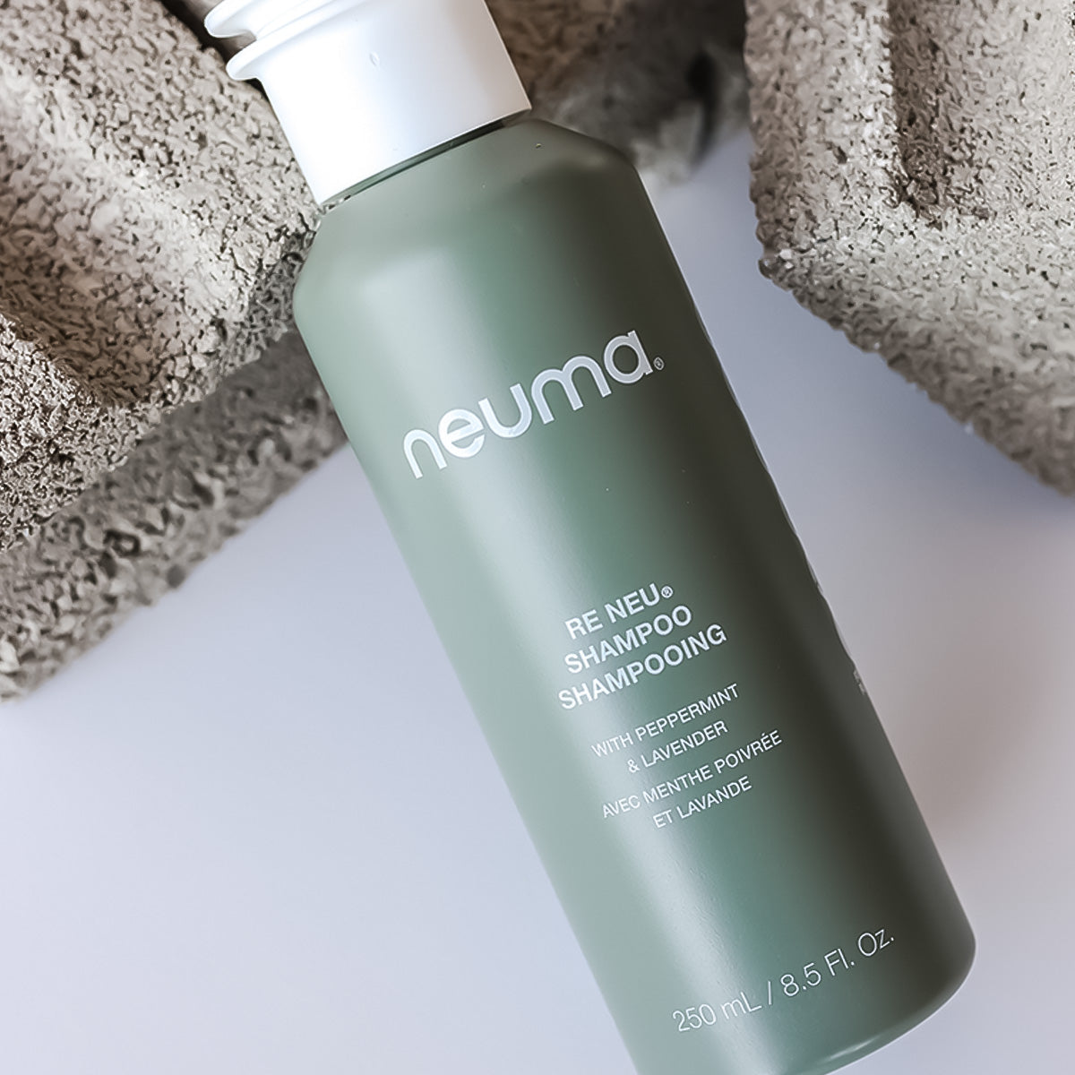 Re Neu Clarifying Shampoo bottle with peppermint and vanilla aroma for clean, soft, vibrant hair; 250ml on a concrete background.