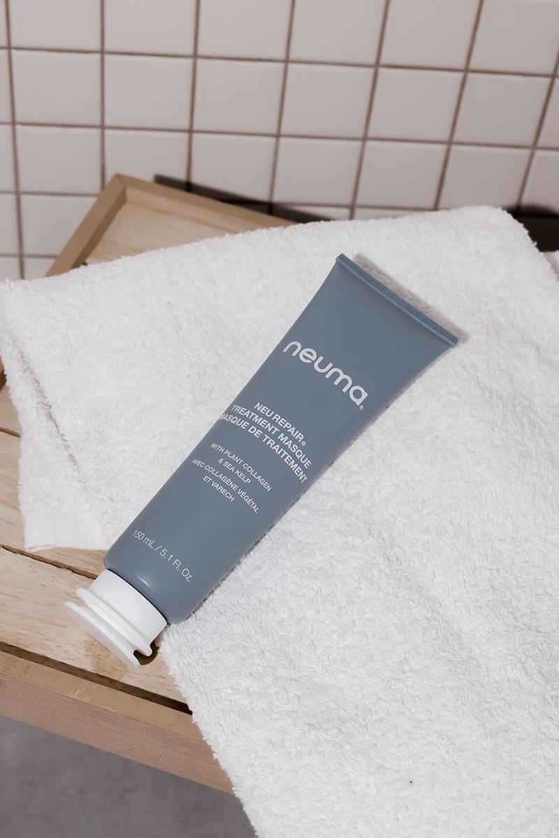 Neu Repair Treatment Masque tube on a white towel, designed to restore and rejuvenate dry, damaged hair with nourishing ingredients.
