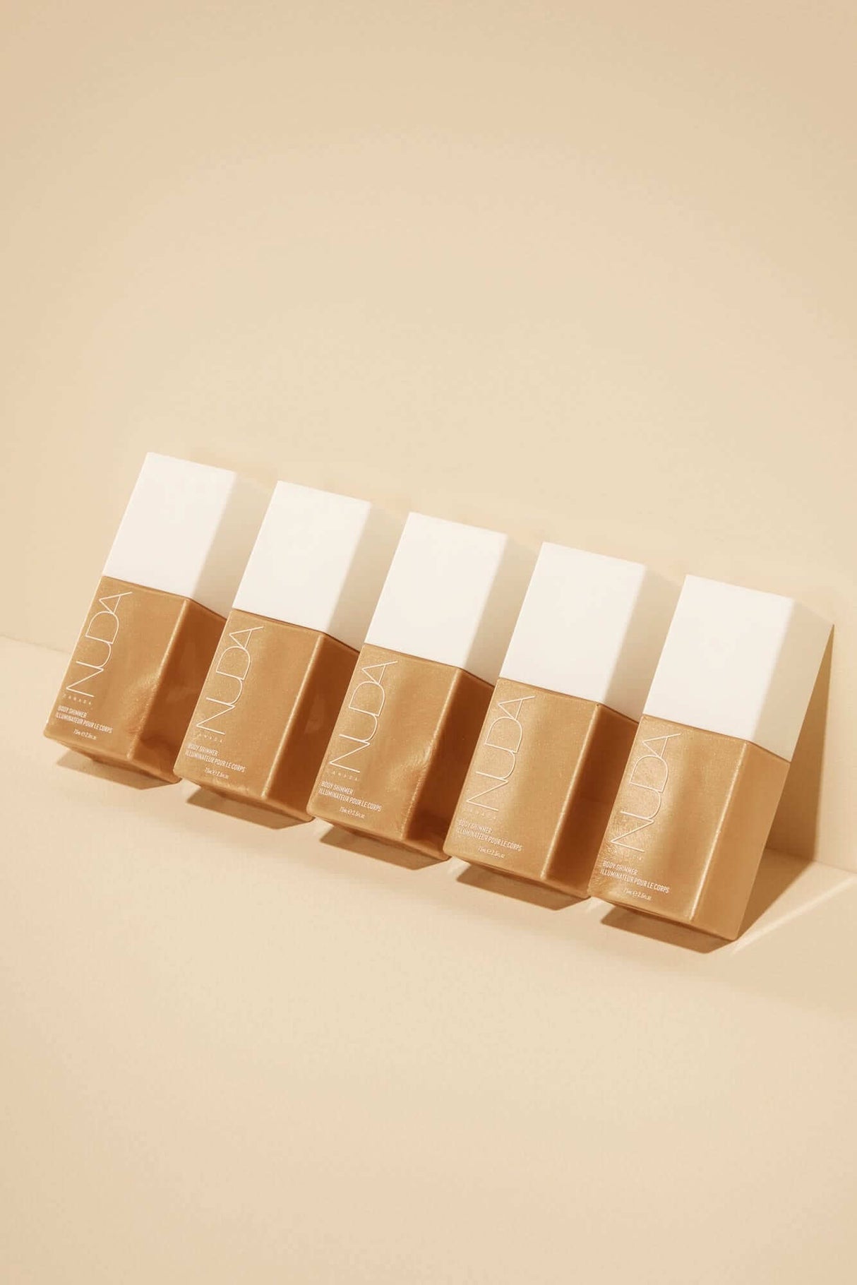 Five bottles of self-tanning glow drops on a neutral background, part of the Ultimate Glow Kit for a radiant complexion.