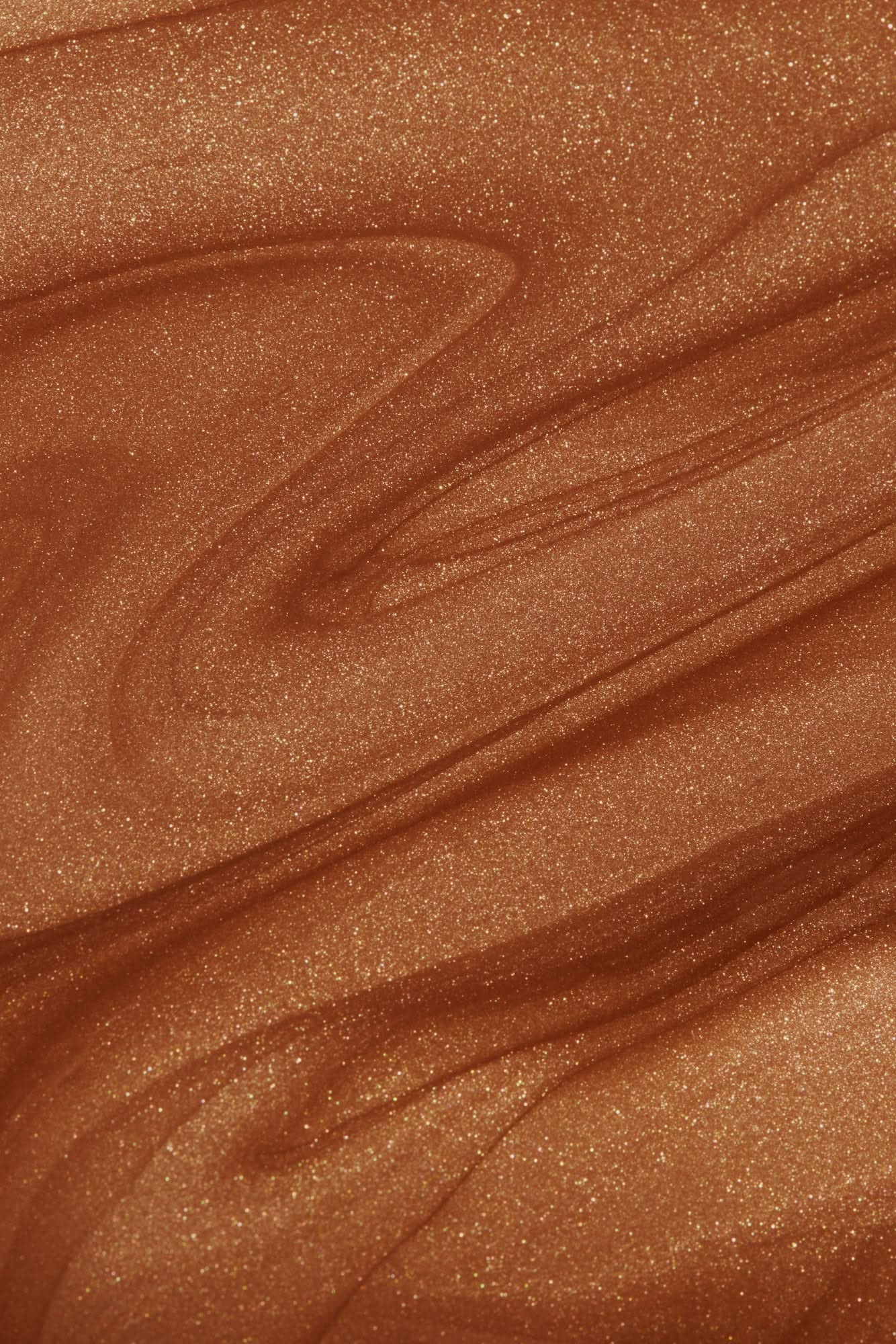 Close-up view of shimmering bronzing glow liquid texture, showcasing smooth, radiant swirls of copper bronze for beauty enhancement.