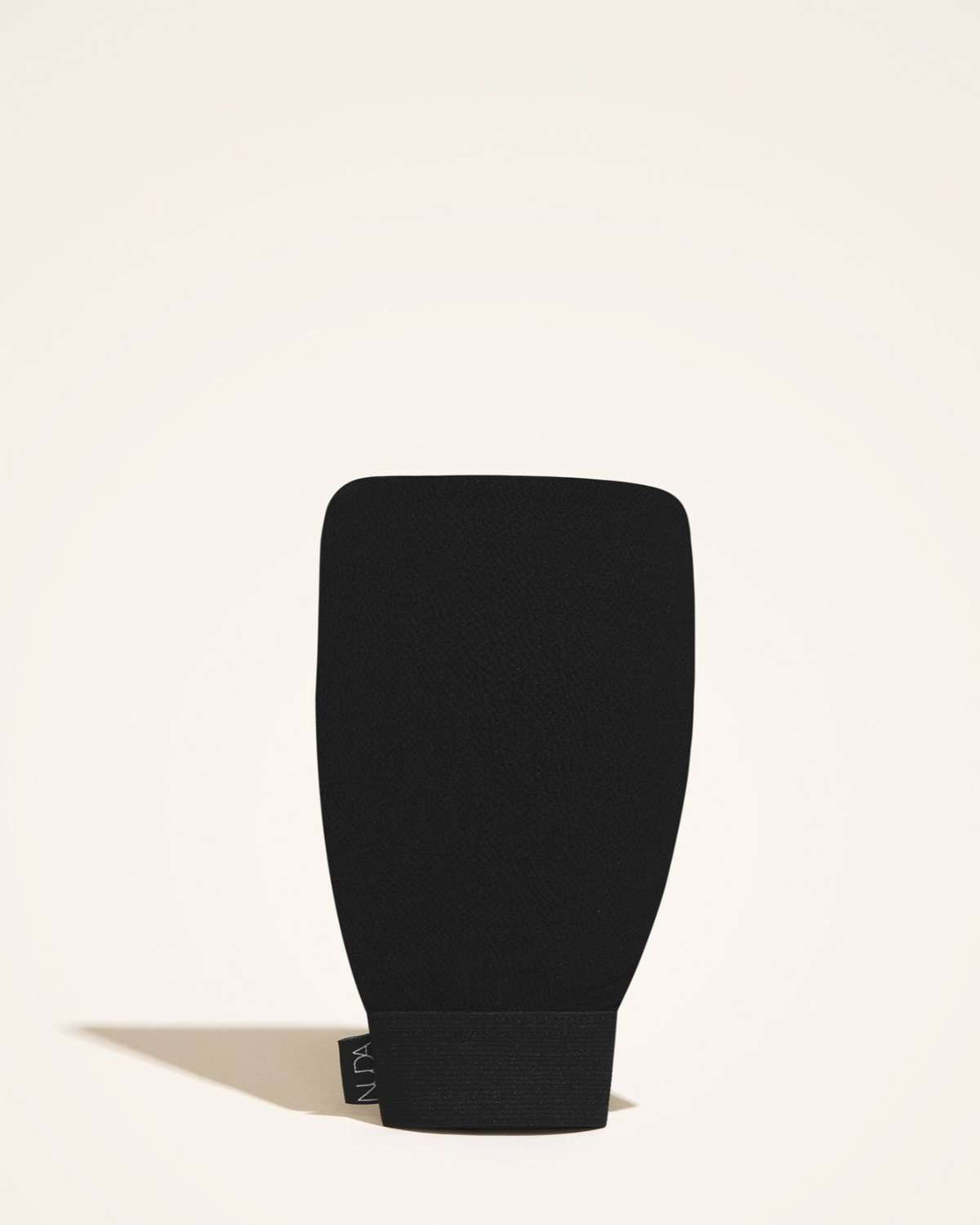 Black exfoliating mitt for removing dull skin and old tan, preparing for new self-tanner application.