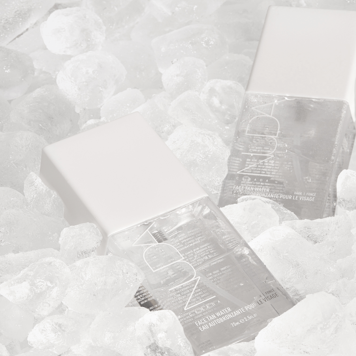 Face Tan Water bottles with aloe, white tea, cucumber extracts, and vitamins on ice, promoting radiant and smooth skin.