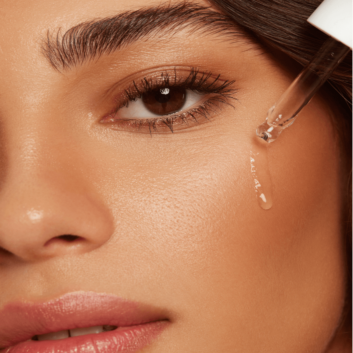 Close-up of woman applying hyaluronic self tanning serum with dropper for radiant skin