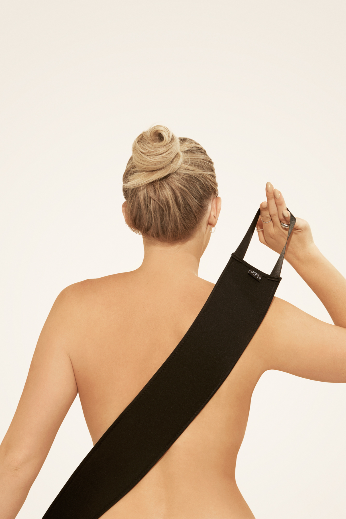 Person using a self tan back applicator for even tanning, showcasing easy reach design on bare back.