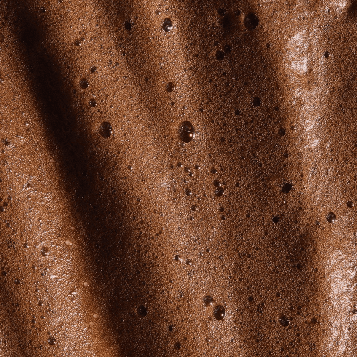 Rich brown texture of self tanning mousse, showcasing its lightweight and velvety consistency for an even, natural-looking complexion.
