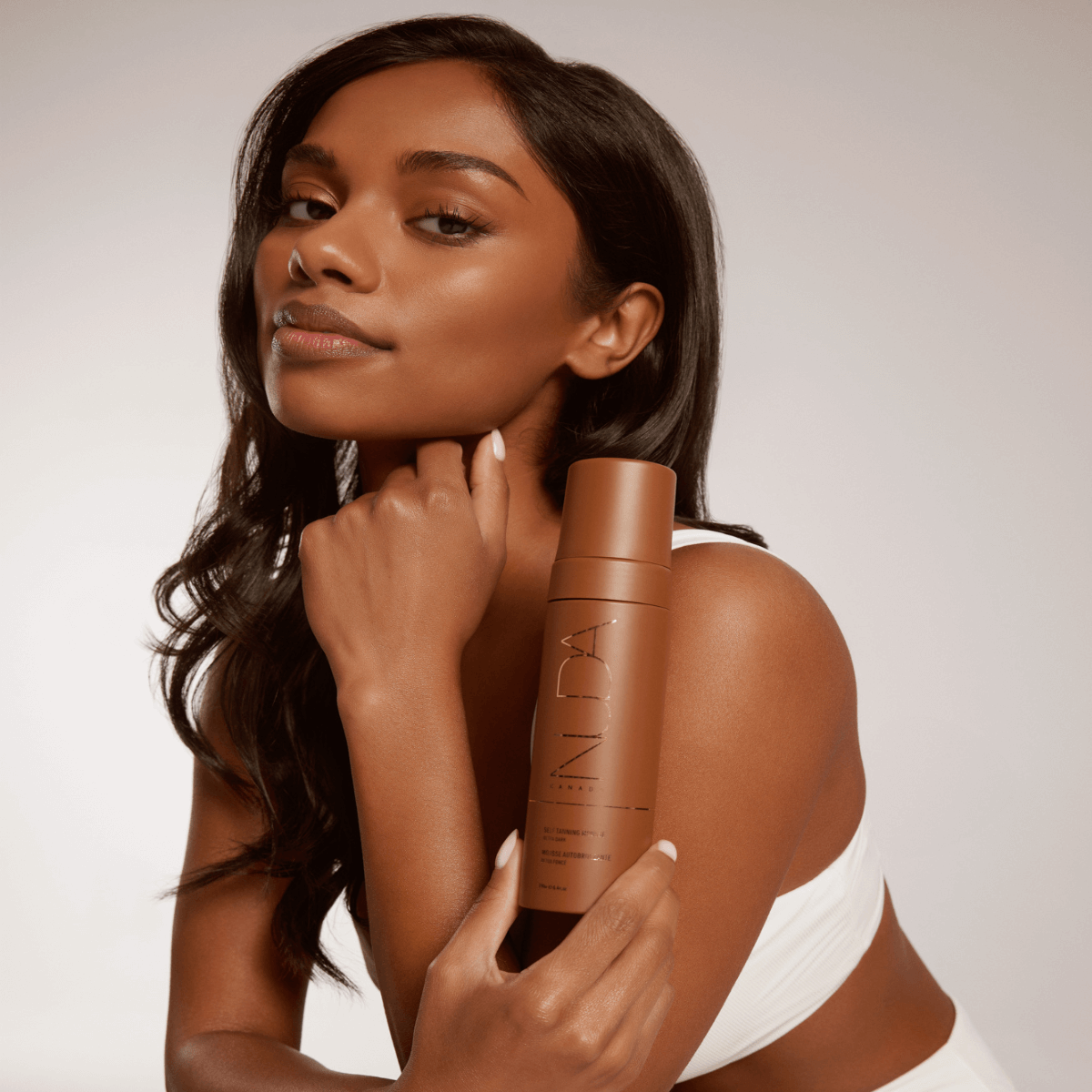 Woman holding Self Tanning Mousse - Ultra Dark, showcasing smooth, radiant skin.
