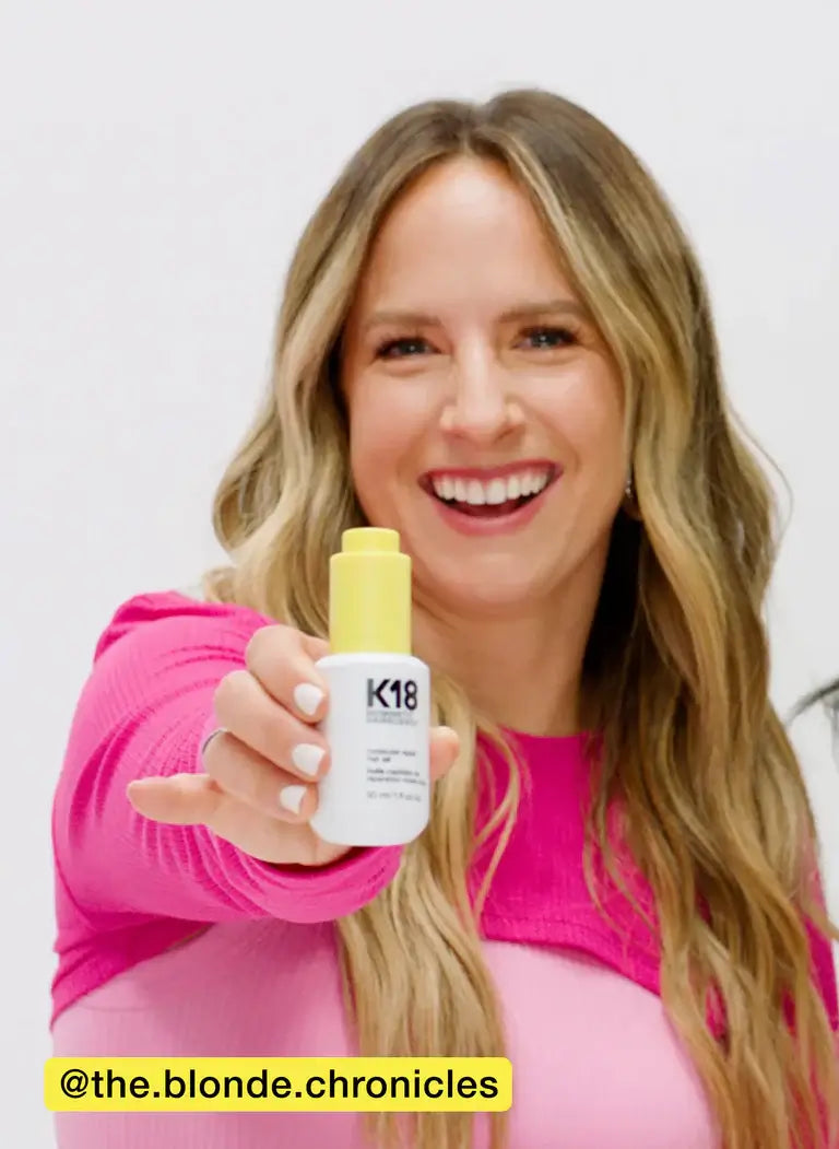 Person holding a bottle of hair repair oil