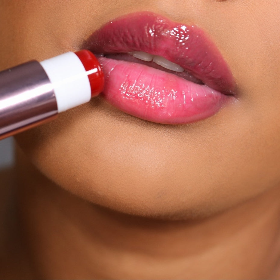 Close-up of lips applying Girlactik Jello Gloss Balm, showcasing a glossy pink finish.