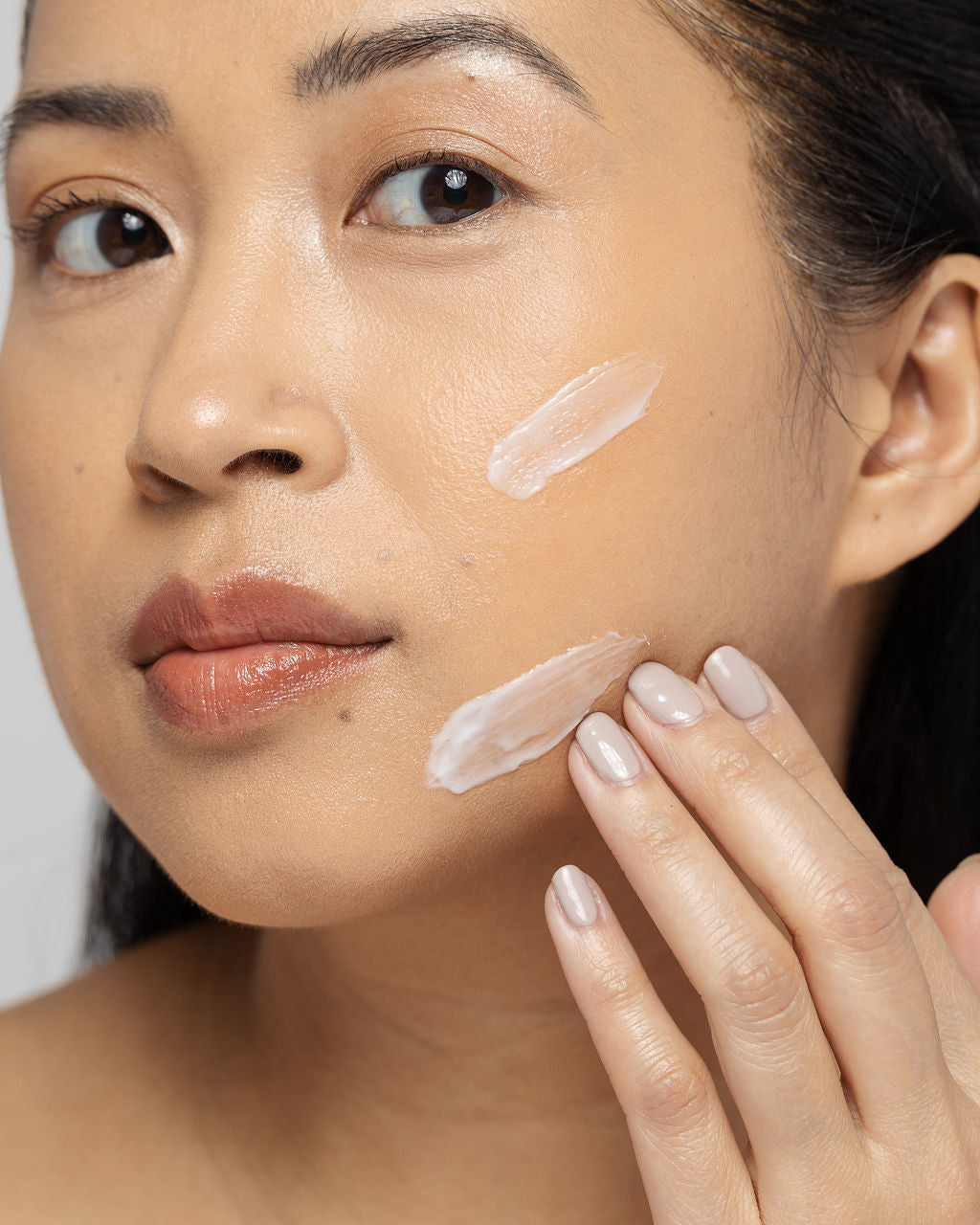 Woman applying Vivier Exfoliant Forte cream to face, enhancing skin texture and tone with Alpha Hydroxy Acids for smoother skin.