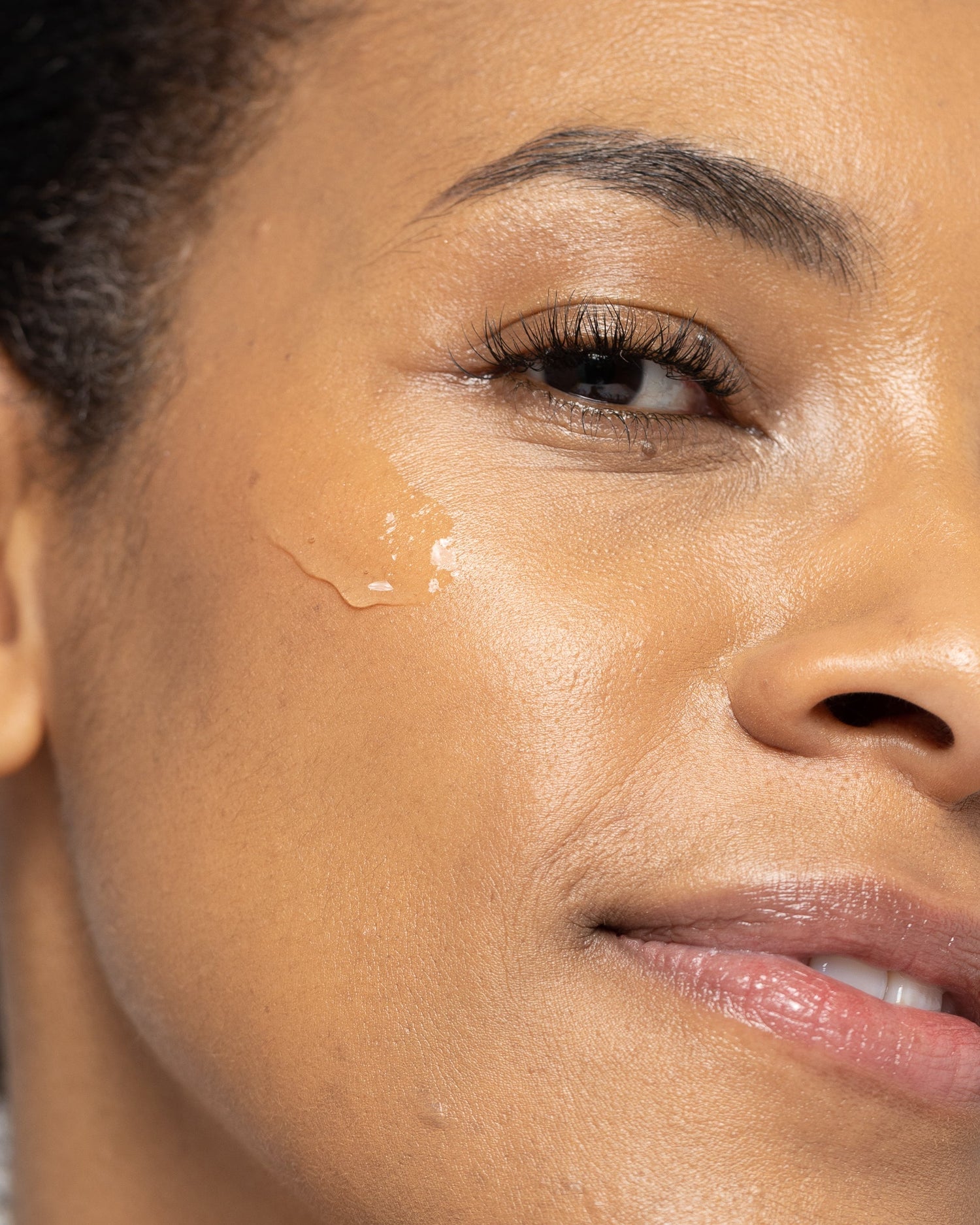 Close-up of a person with HEXAM cleanser on their cheek, highlighting skin hydration and clarity.