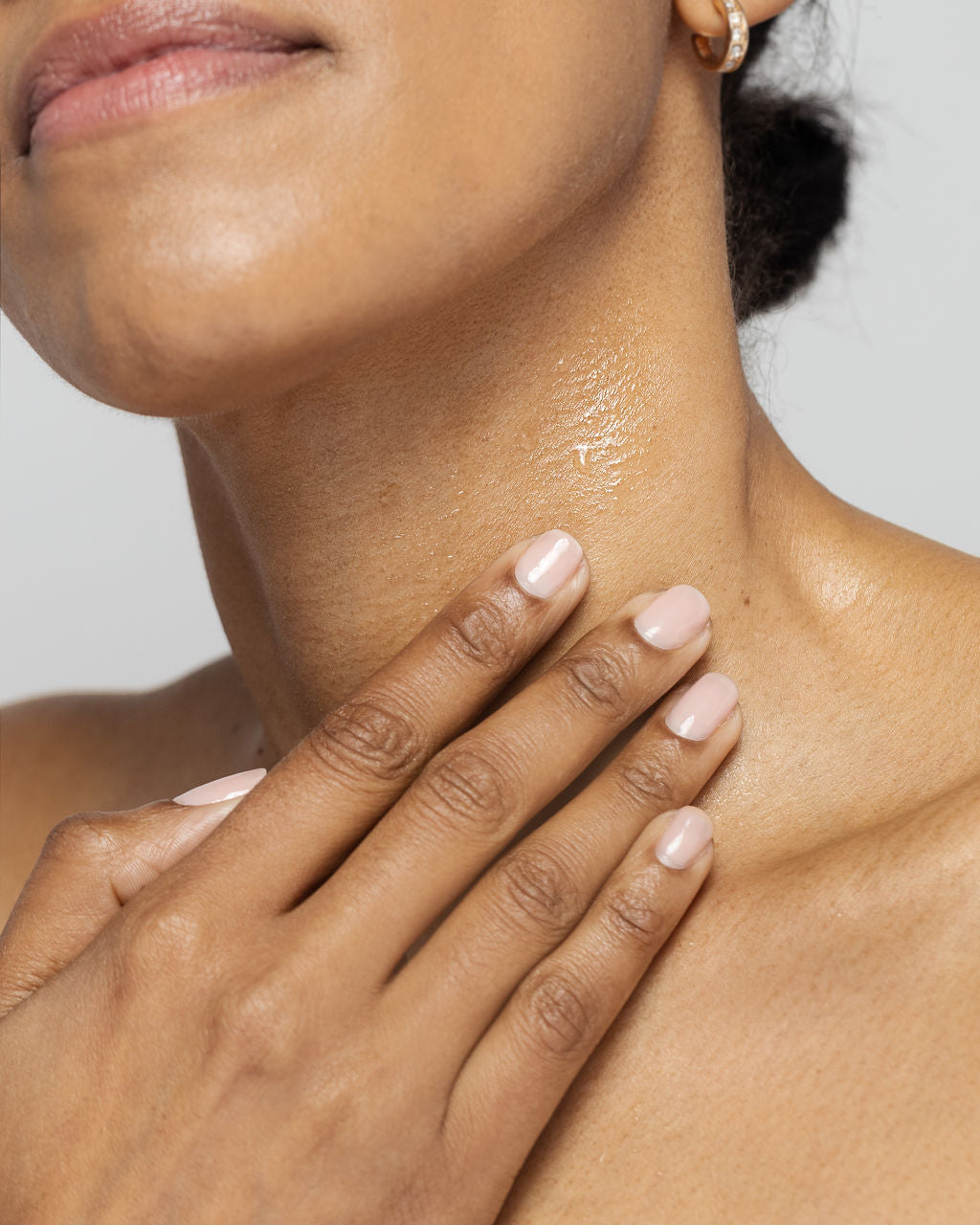 Close-up of a person applying Kine-C antioxidant serum on neck for skin hydration and wrinkle reduction.