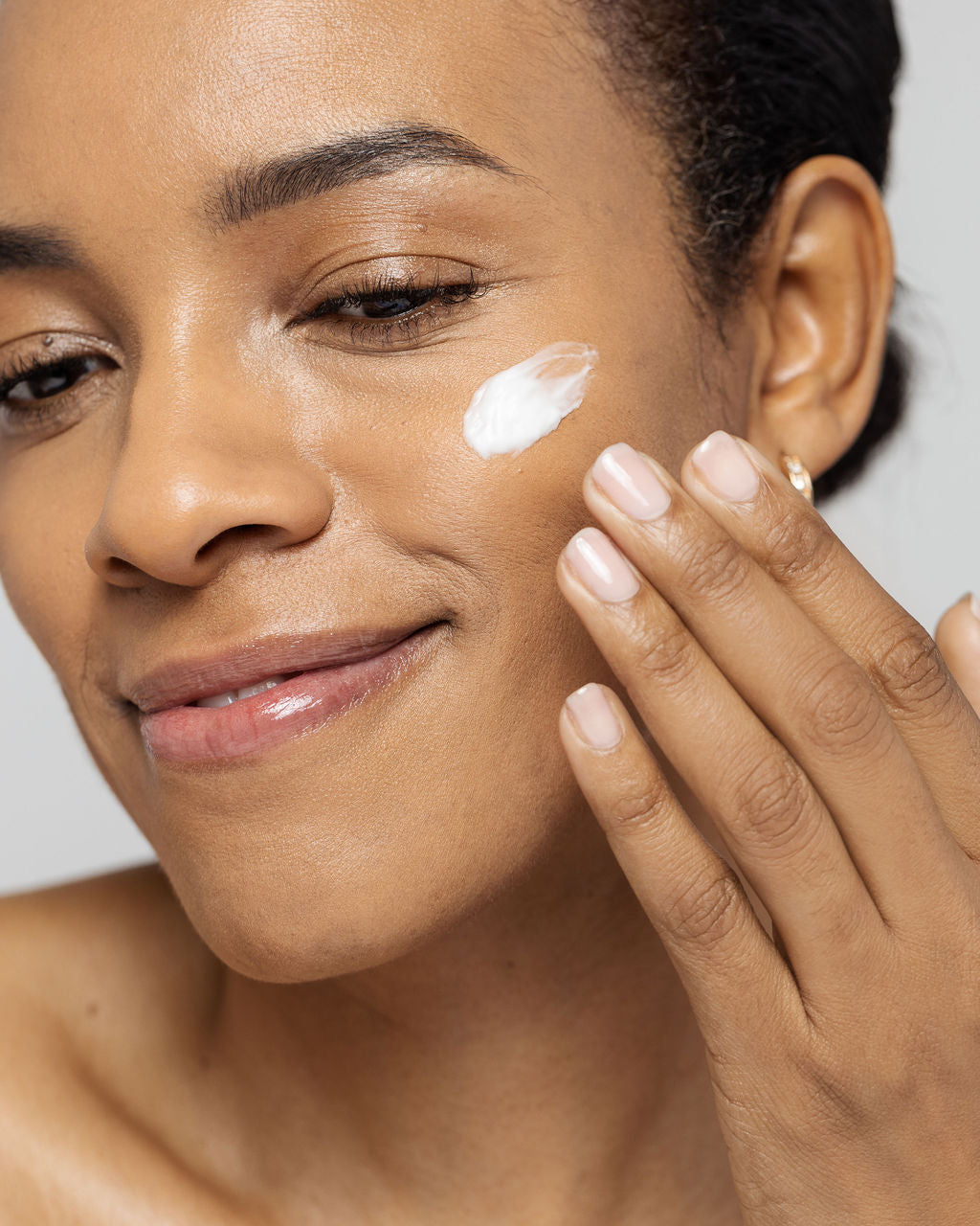 Woman applying Vivier LEXXEL hypoallergenic moisturizer on her face for dry, sensitive skin hydration and calming.