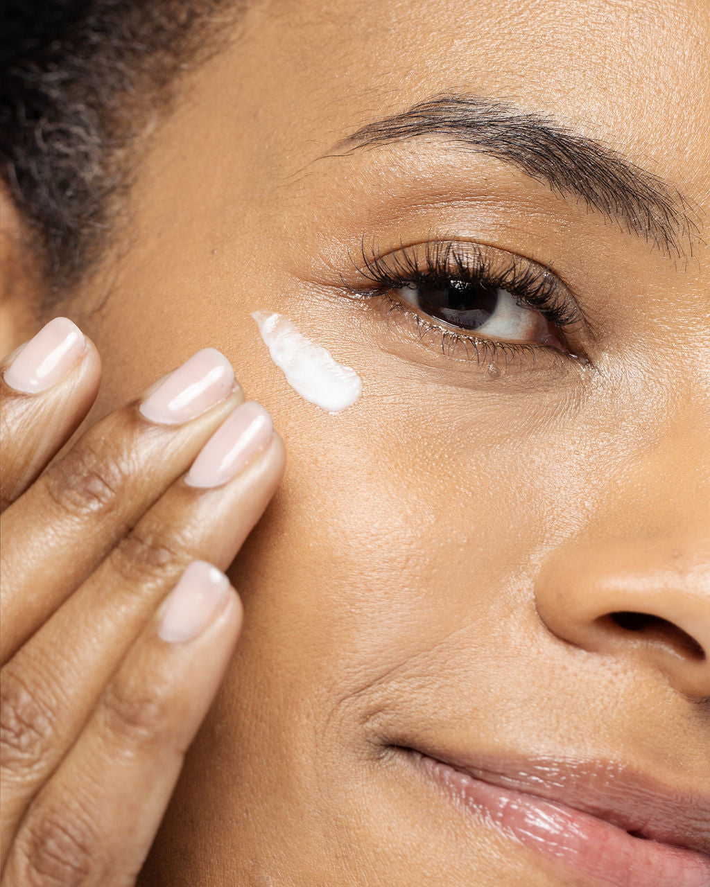 Close-up of woman applying Radiant Eye Contour Cream under eye, highlighting skincare routine for hydration and anti-aging benefits.