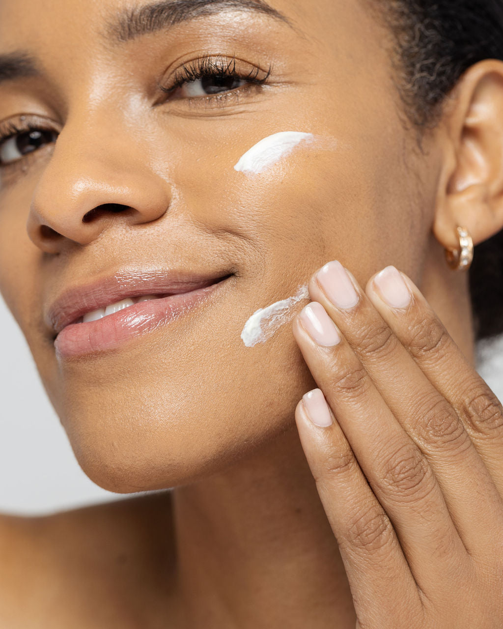 Person applying skincare product on face, showing smooth skin texture and anti-aging benefits of Vivier Retinol 1.0%.