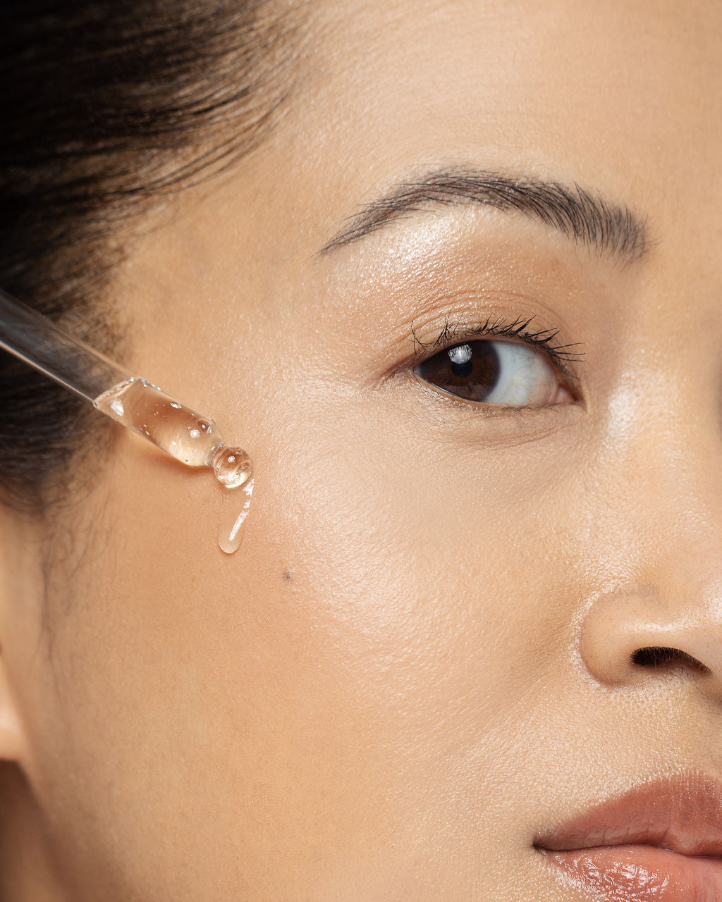 Applying Vivier Serum 10 with Vitamin C to enhance skin radiance and reduce fine lines on a woman's face.