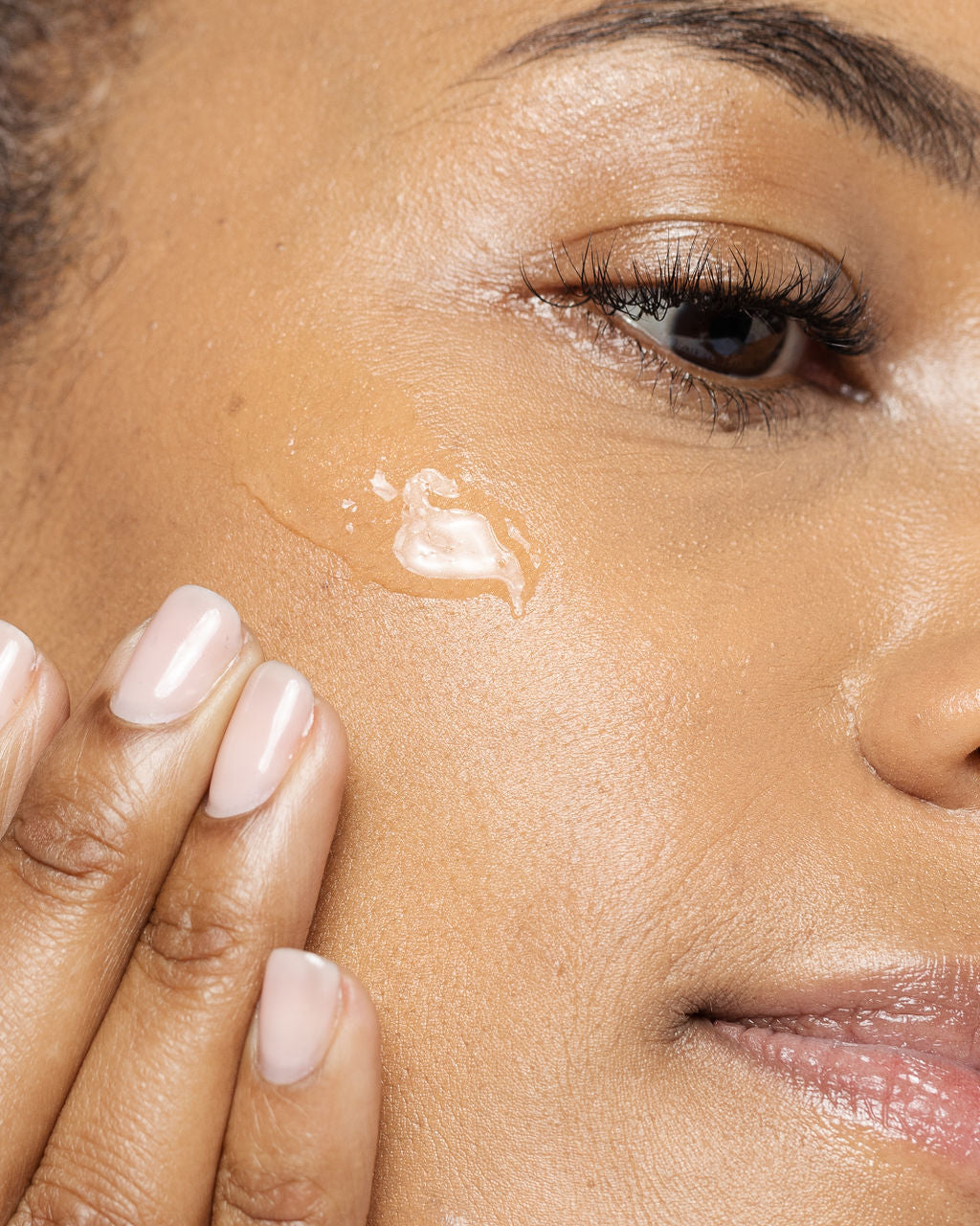 Woman applying Vivier Ultimage™ lightweight gel with hyaluronic acid to her cheek for hydration and wrinkle reduction.