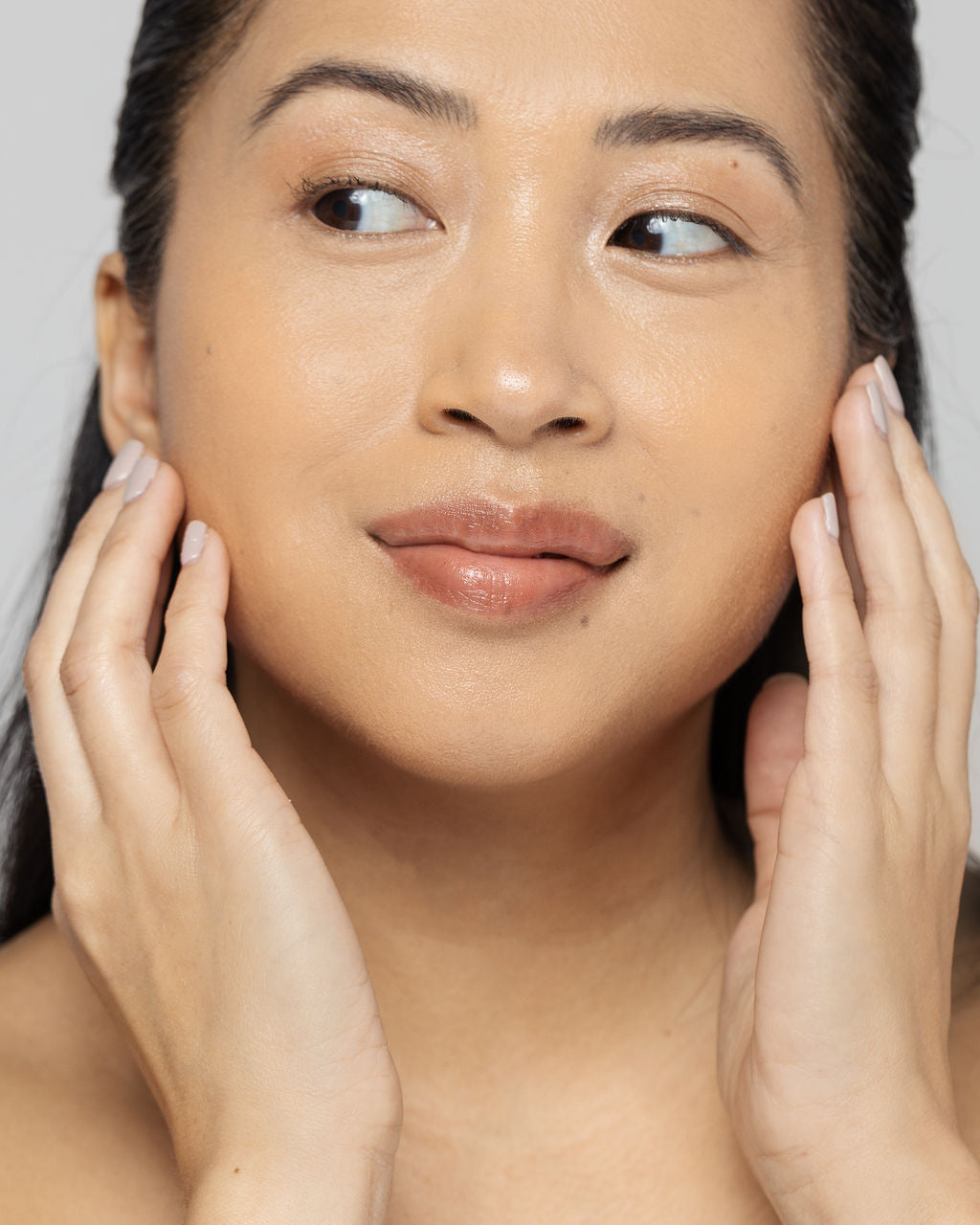 Woman touching her radiant, smooth face after using Vitamin C scrub, promoting clear skin and rejuvenation.
