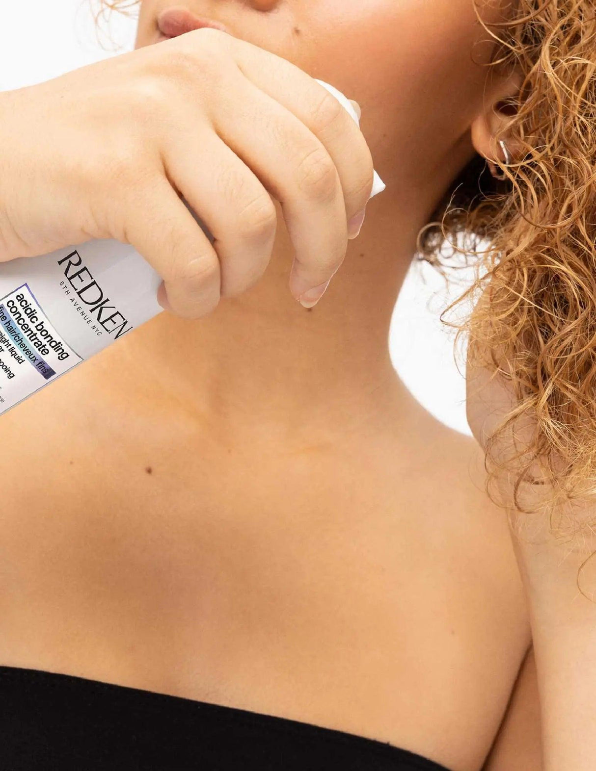 Woman using Redken Acidic Bonding Concentrate Lightweight Conditioner for strong, healthy hair.