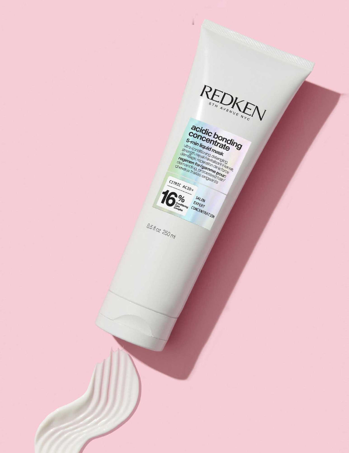 Redken Acidic Bonding Concentrate Liquid Mask tube on pink background with cream texture, ideal for damaged hair treatment.