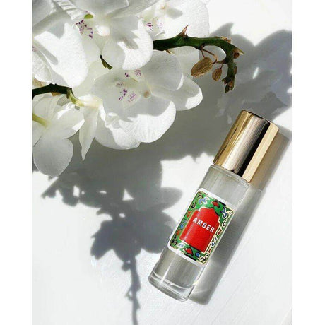 Amber Roll On Perfume by Nemat with orchid background, showcasing the elegant fragrance bottle and luxurious design.