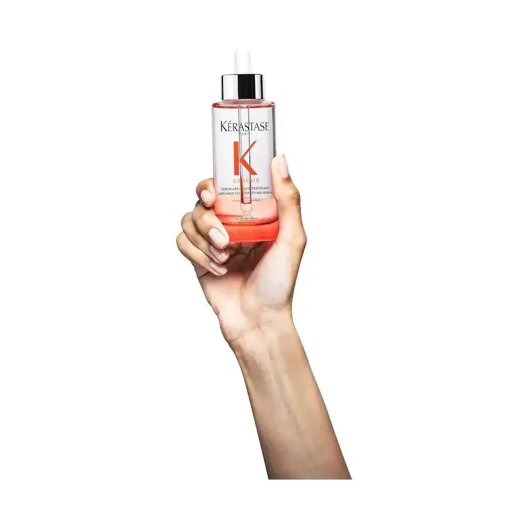 Hand holding Kérastase Anti-Breakage Fortifying Serum bottle for strengthening and reinforcing damaged hair.