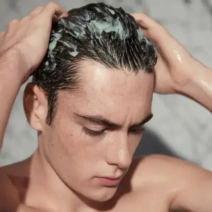 Man applying Kerastase Argile Équilibrante clay shampoo to cleanse and balance oily scalp.