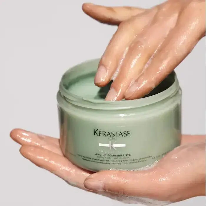 Kerastase Argile Équilibrante clay shampoo in jar with hands applying product.