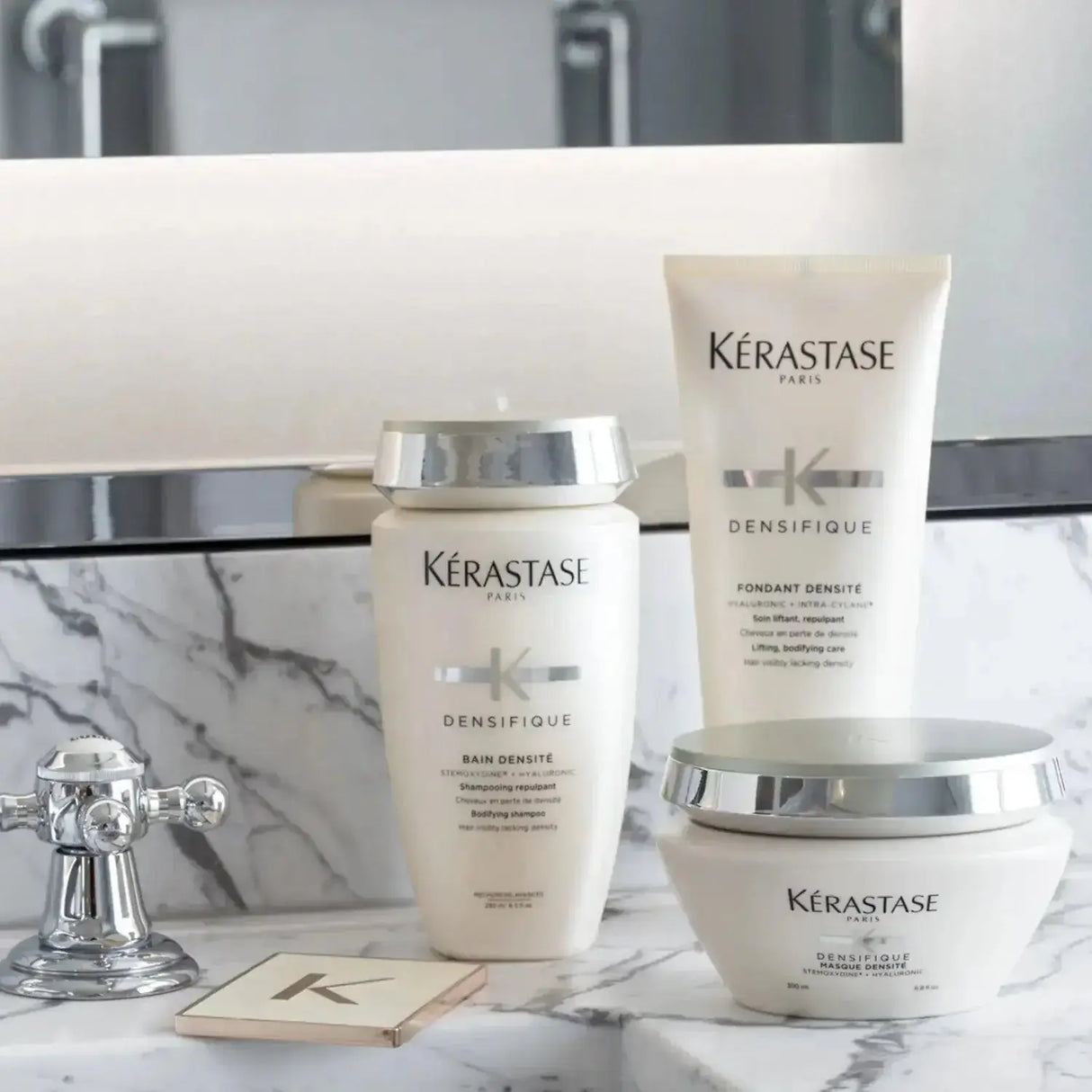 Kérastase Bain Densité shampoo and products for enhancing hair density, displayed on a marble bathroom counter.