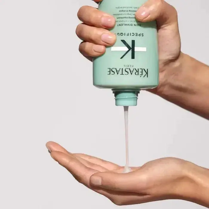 Kérastase Bain Divalent shampoo for oily roots and dry ends being poured into hand, green bottle, hair care product.