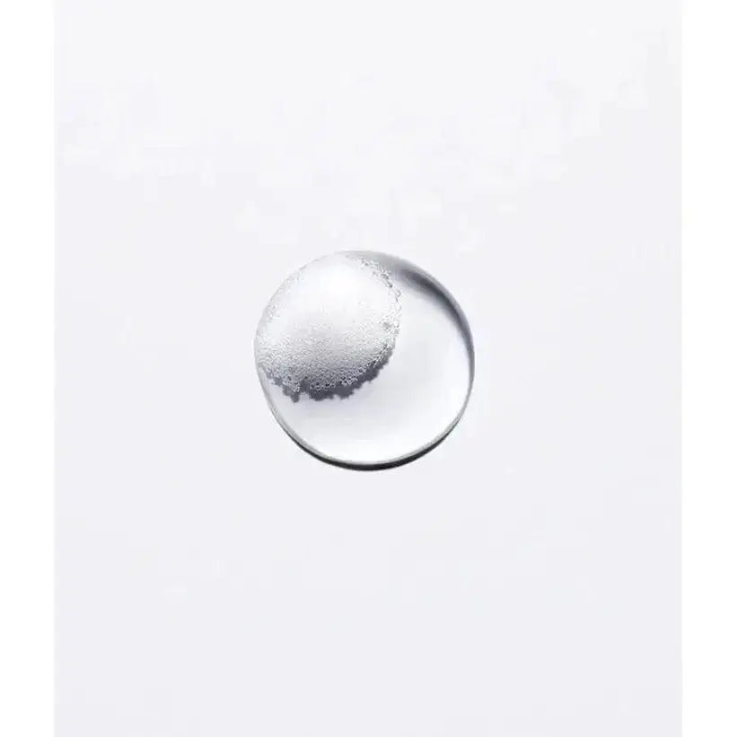 Close-up of a transparent liquid drop on a white background, representing the formula of Kérastase Bain Hydra Fortifiant shampoo.