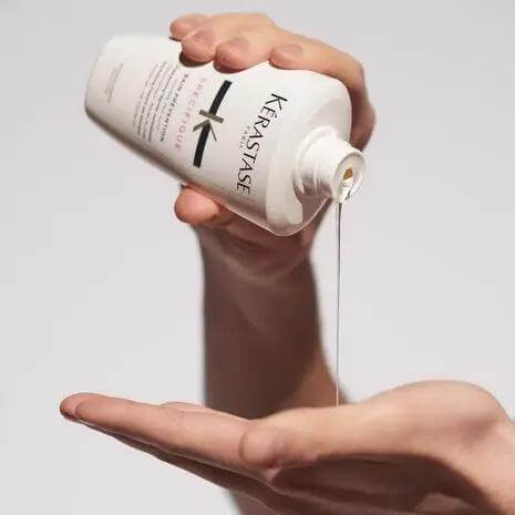 Kérastase Bain Prévention Shampoo being poured into hand, ideal for hair thinning and promoting growth across all textures.