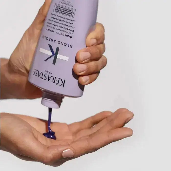 Person pouring Kerastase Bain Ultra-Violet purple shampoo onto hand, targeting brassy tones in blonde and gray hair.