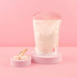 All Natural Bath Salts with Neroli & Grapefruit in pink packaging on a pedestal, next to a scoop of salts.