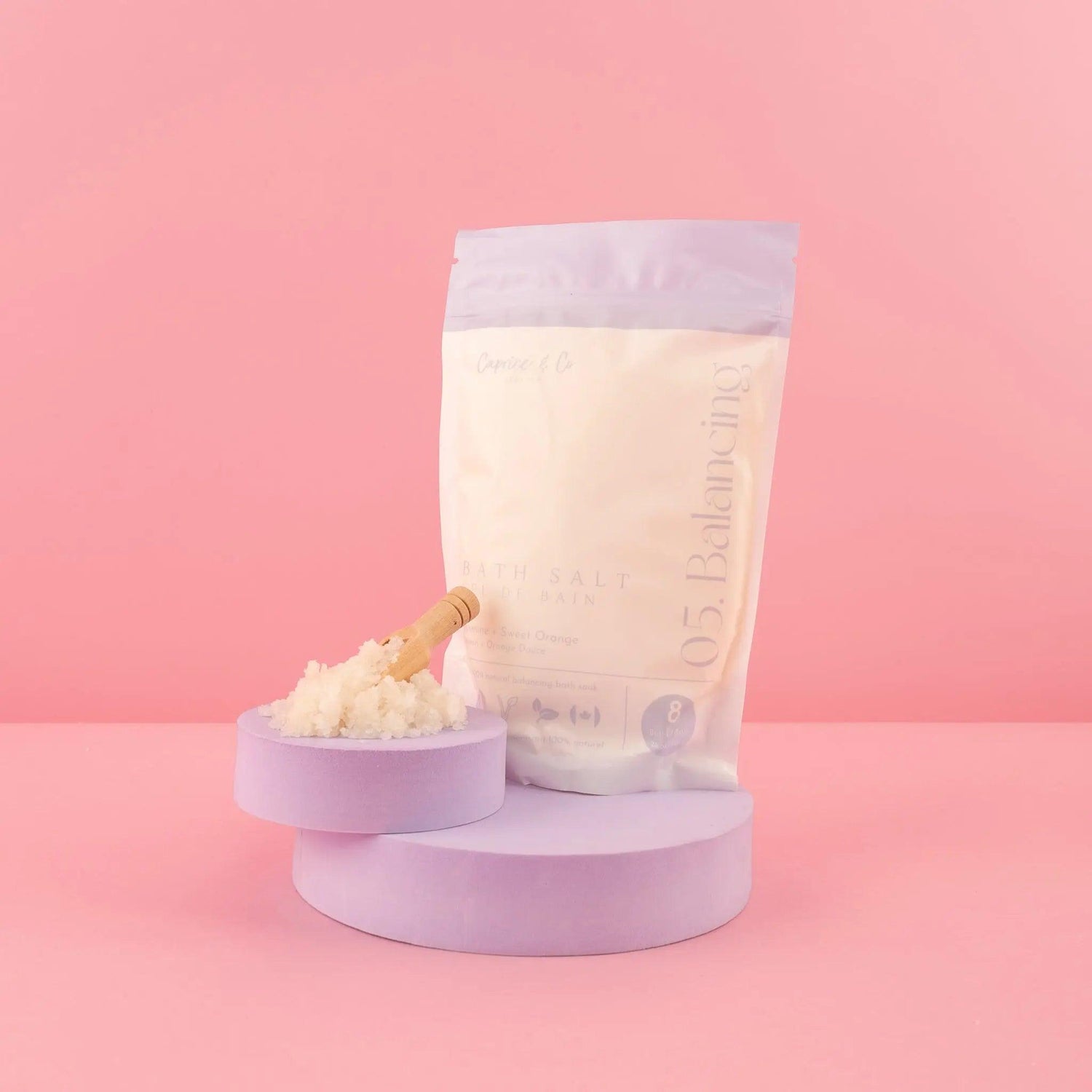 All Natural Bath Salts in Lavender Packaging with Wooden Spoon on Pink Background