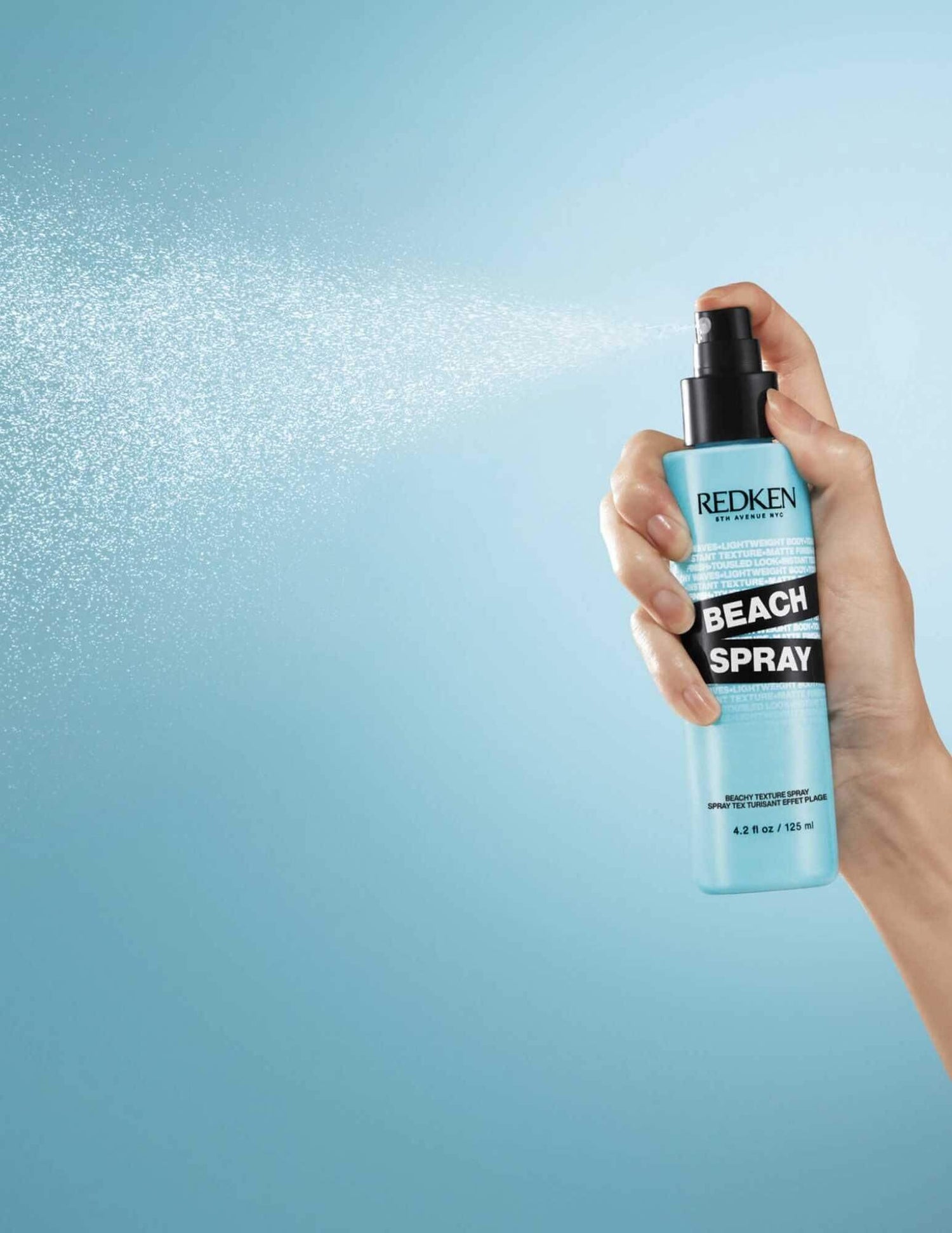 Redken Beach Spray bottle creating beachy waves with texturizing salt spray for effortless, natural hair texture and volume.