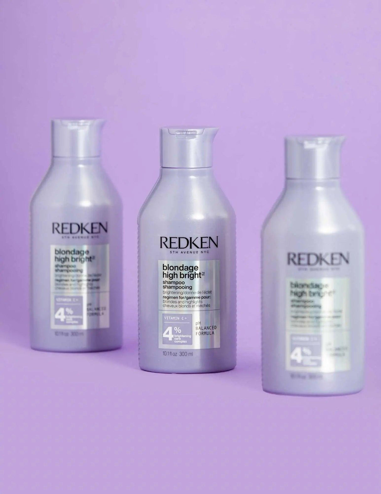 Redken Blondage High Bright Shampoo bottles for vibrant blonde hair against a lavender background, addressing brassiness and color fading.