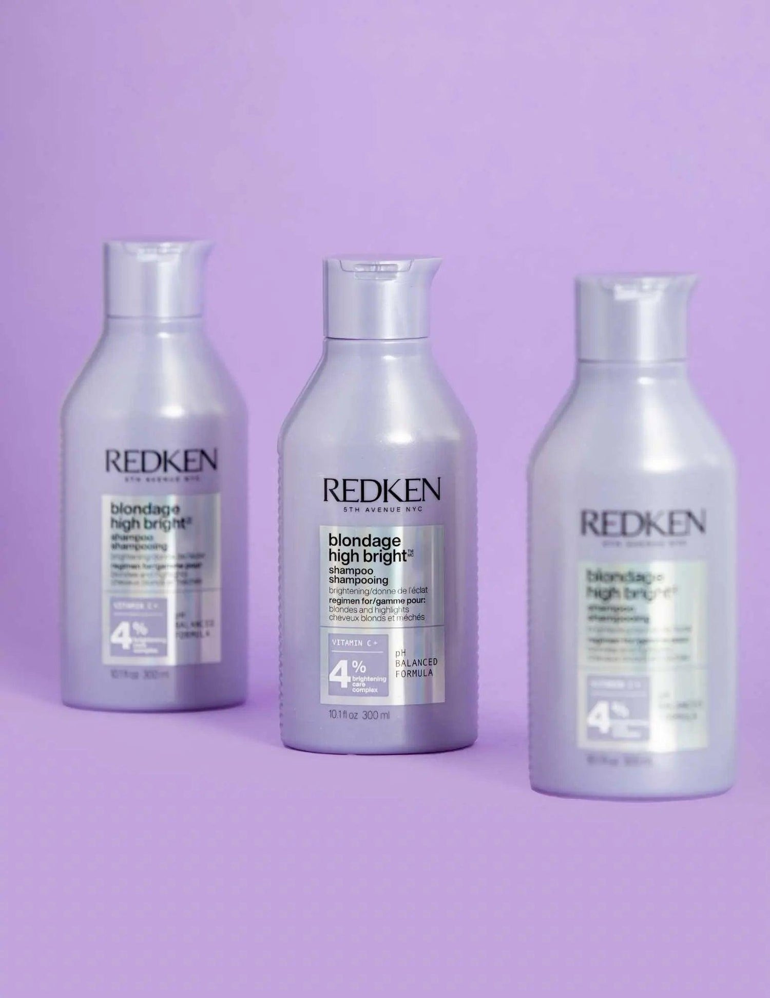Redken Blondage High Bright Shampoo bottles for vibrant blonde hair against a lavender background, addressing brassiness and color fading.