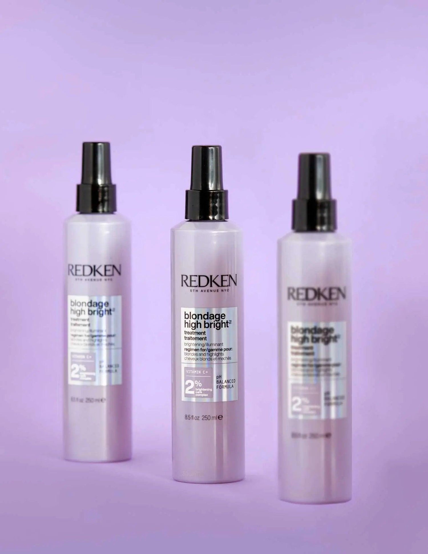 Three bottles of Redken Blondage High Bright Treatment for blonde hair, neutralizing brassiness and boosting brightness on a lavender background.