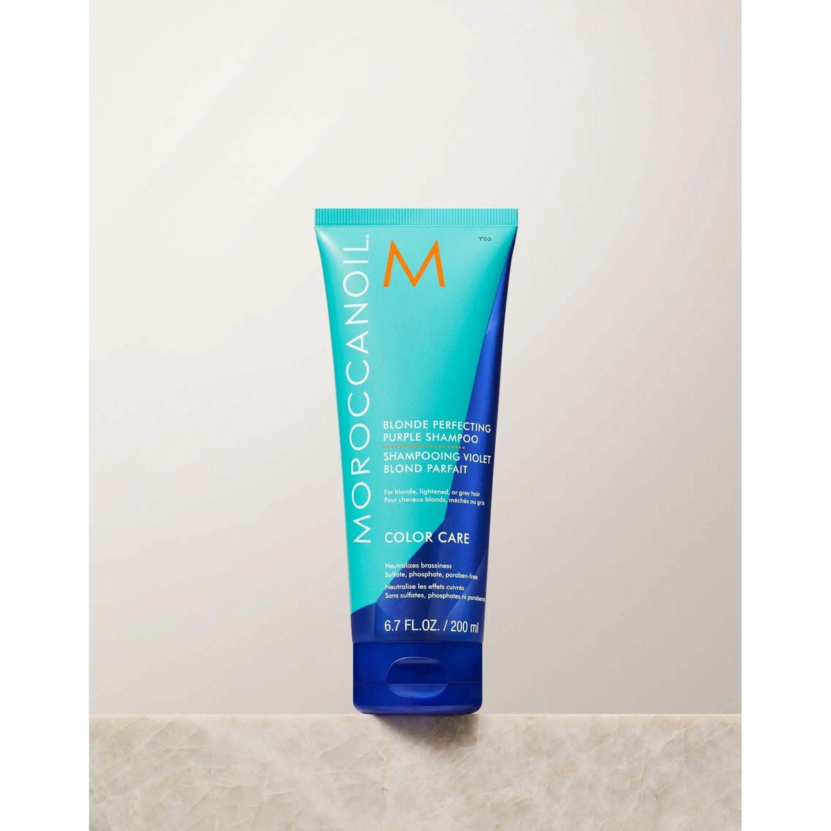 Moroccanoil Blonde Perfecting Purple Shampoo bottle, sulfate-free, enhances color depth and repairs hair with ArganID technology.